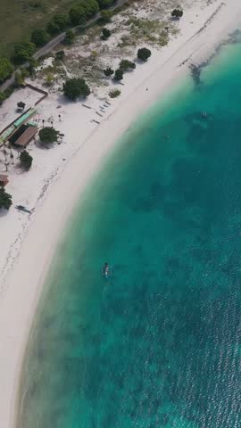 Beach Scene Overview.Sunny Coastal Shoreline With Boats.Beautiful Turquoise Beach With Boats Under Sunlight.Scenic Aerial Image Showcasing Vibrant Beach,Tanjung Aan,Kuta,Lombok,Vertical video