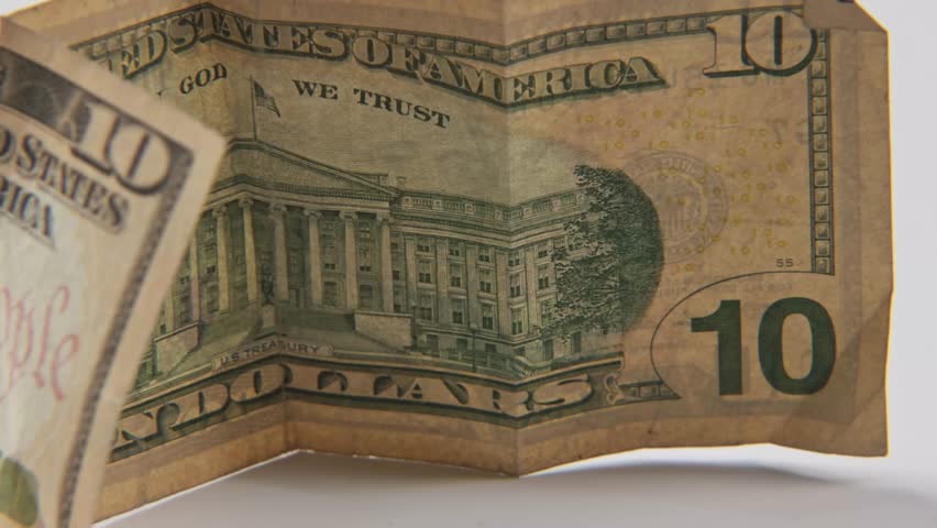 Alexander Hamilton the first U.S. Secretary of the Treasury portrait on printed ten 10 dollar bill of United States of America cash and printed treasury bills in close up and studio slo mo slow motion