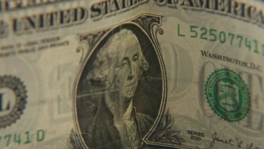 One dollar bill worth 1 hundred cents of American United States paper cash money with first president face of George Washington on economy bills in a tight close up of portrait and eagle textures slow