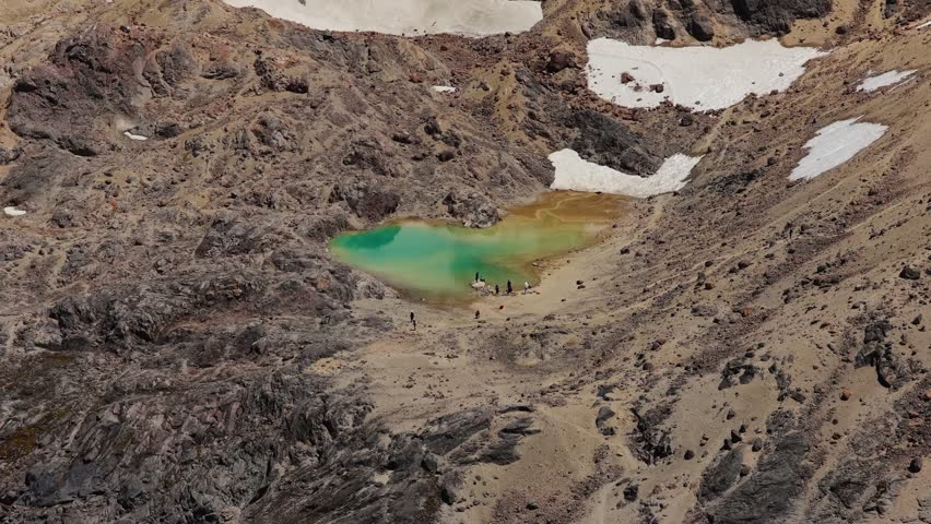 Aerial drone view of Laguna Verde, a small turquoise crater lake on the slopes of Cayambe volcano in the Ecuadorian Andes, surrounded by rugged volcanic terrain and high altitude landscape.