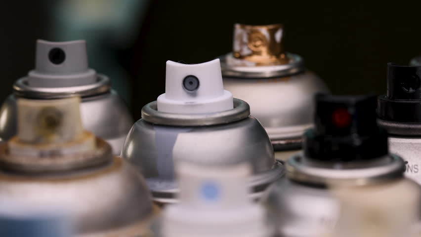 Various Spray Paint Can Nozzles and Colours Close Up Backwards