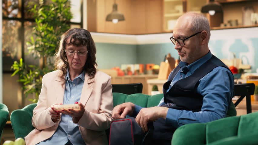 Old man reading for blood pressure monitoring and woman takes vitamins, improving quality of life for wellness and recovery. Retirees couple doing in-home daily care routine, wellbeing.
