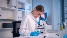 Caucasian female scientist in white lab coat working in the laboratory. Attractive young researcher technician conducting medical research using microscope, focusing on samples in modern science lab. - Powered by Shutterstock - Get 15% off with code: PIKWIZARD15