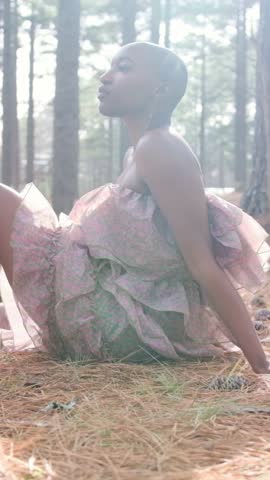 Beautiful black woman with shaved head sitting in a pine forest