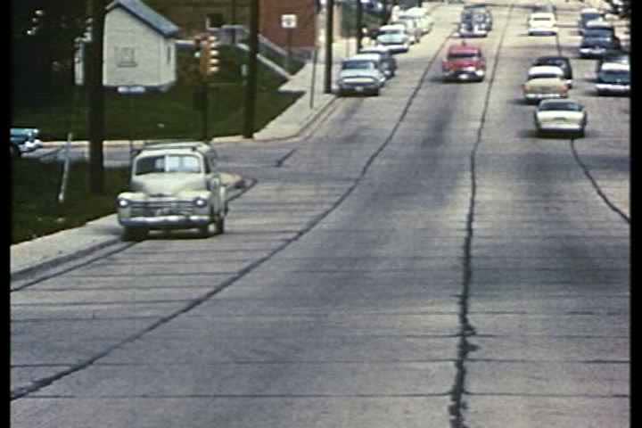 1950s - A 1950 ambulance races down a street and pulls up to the emergency room at a hospital.