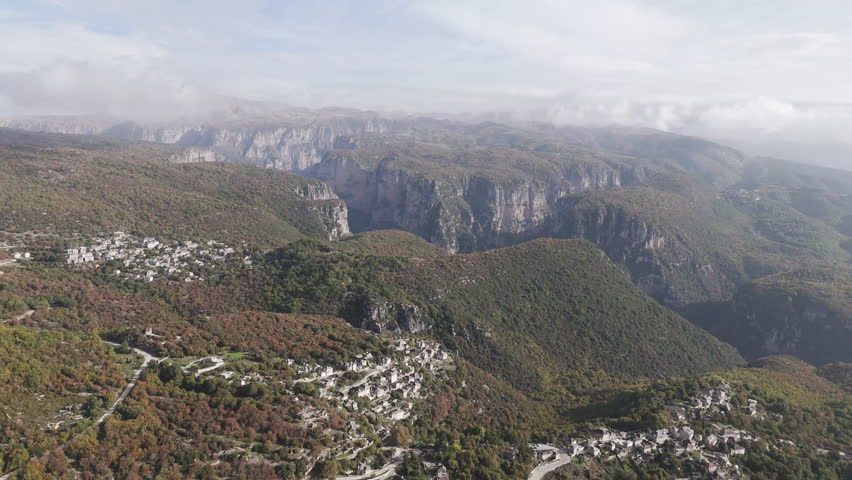 Aerial overview of Vikos Gorge cliffs and dense mist rolling through rugged mountainous terrain with Monodendri in foreground