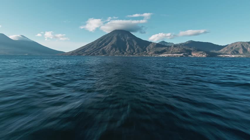 Fast flying towards massive volcano mountain with cloud cap over Lake Atilan, FPV drone view