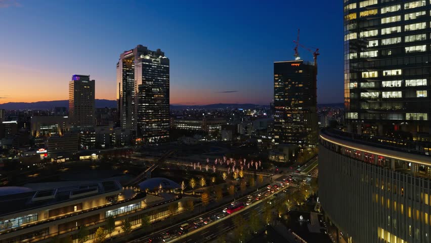 Stunning aerial night view of Osaka city skyline at twilight with illuminated skyscrapers and traffic.