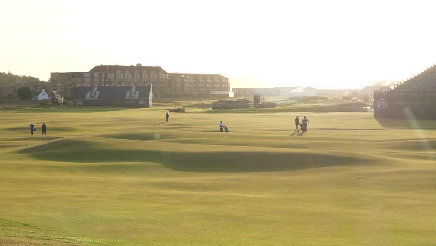 Golfers walking across the beautiful and legendary Old Course at St Andrews in Scotland during sunset