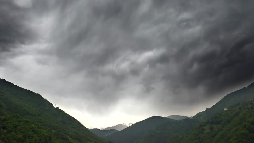 Time lapse storm clouds before rain over dense mixed forest valley in Mount Aspiring National Park. Darkening skies sweep across the wooded valley revealing dramatic weather patterns in New Zealand.