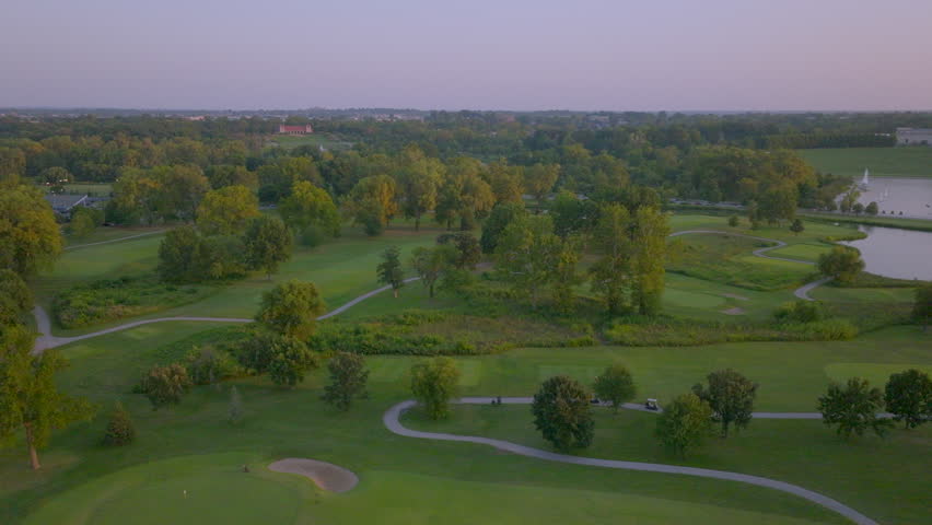 Stunning aerial drifting over Forest Park at sunset, capturing the St. Louis Art Museum and Grand Basin. Features golden hour light, tranquil water, and a picturesque urban landscape in Missouri