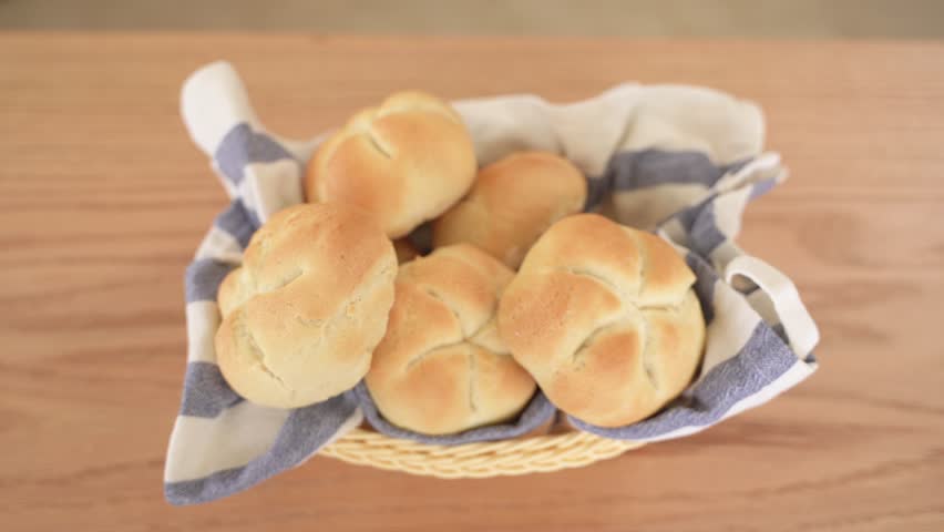 Top Down View of Freshly Baked Kaiser Bread on Striped Towel in Wooden Basket