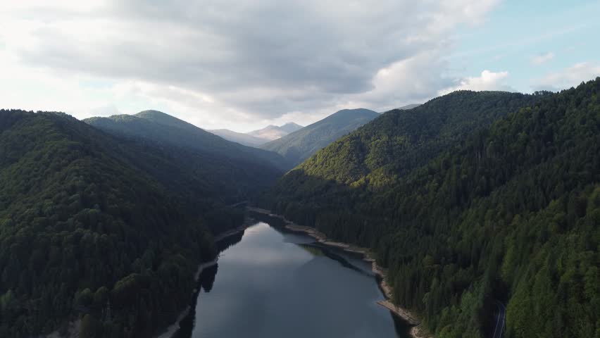 Aerial shot flying over the Fagaras mountain range and Lake Vidraru in Romania