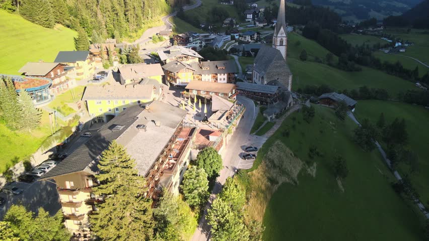  Shot of tower in rural valley town Heiligenblut, Austria.Flying by St Vincent church in Heiligenblut in austrian Alps, popular tourist destination with highest peaks of Austria in the background.