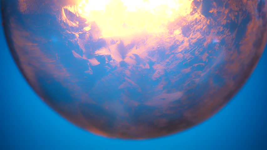 A close up of a glowing and fading incandescent light bulb against a blue background, creating a vibrant contrast.