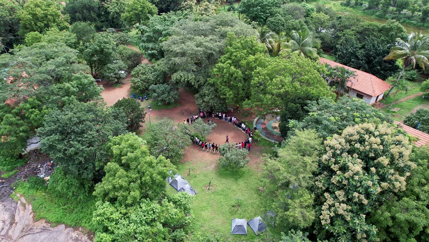 Drone view of trekkers gathering on Ramanagara Hill, surrounded by dense green forest highlighting scenic trails lush vegetation and natural beauty
