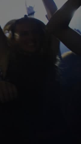 Vertical video: Front woman closing eyes while crowd pressing in, friend dancing, club bars pulsing. Nightlife, partygoer, dance, led, glow, haze, vertical video