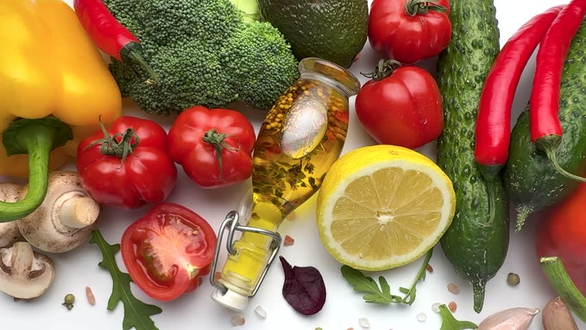 Variety of colorful fresh organic vegetables with olive oil and spices isolated on white background