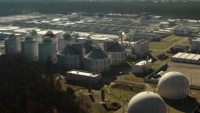 Metropolitan infrastructure generates renewable energy by processing liquid waste and urban sewage pollution in specialized digester domes at industrial purification plant complex.