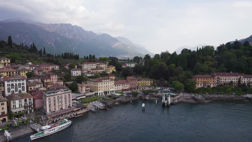 The Lakefront City Of Bellagio With Ferry Station In Como Lake, Northern Italy. Aerial Wide Shot