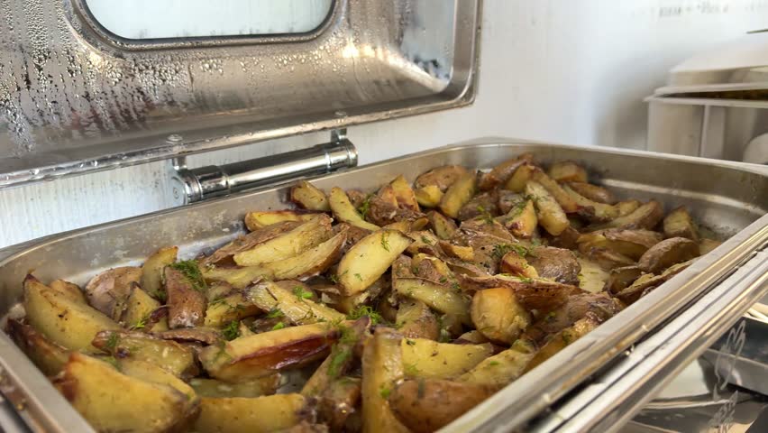 Baked potatoes with mushrooms in a plate on the table. Girl picks up potatoes with a fork