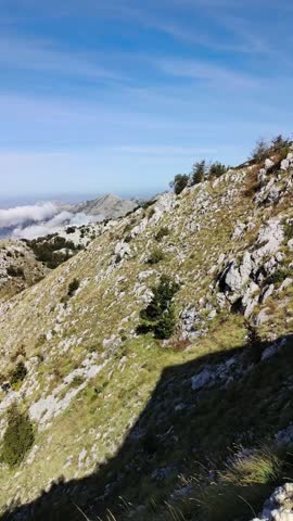 Vertical mountain landscape above the clouds with blue sky and dramatic valley view.