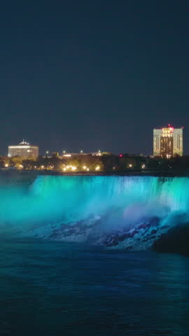 Niagara Falls illuminated at night with colorful lights reflecting in mist and water, famous waterfall landmark on the USA Canada border.
