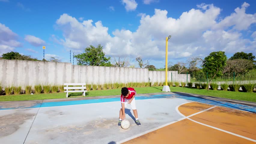 A boy is playing with a soccer ball in a park