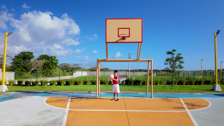 A young boy stands in front of a basketball hoop