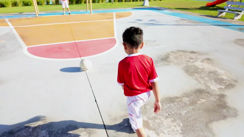 A boy in a red shirt is playing with a soccer ball on a court