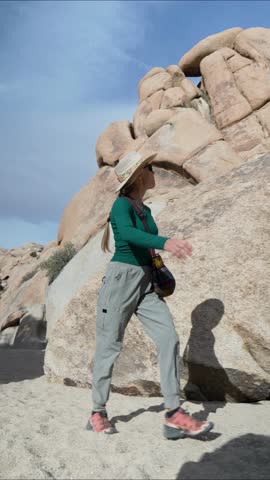 Mature woman walks along the Willow Hole trail in Joshua Tree National Park, enjoying the desert rocks and clear skies during her hike.