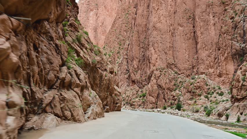 Scenic road trip through the narrow Todgha Gorge with high red cliffs in the Atlas Mountains