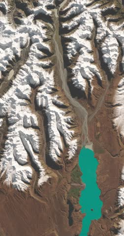 Panoramic top view of mountains with snow line visible on sunny day. Camera is zooming in, rotating counterclockwise. Vertical video. Animation based on image by NASA