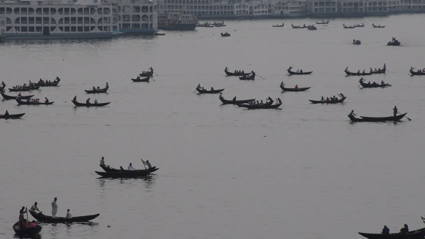 DHAKA, BANGLADESH – MAY 09: Small wooden boats are seen carrying passengers to cross the Buriganga river in Dhaka, Bangladesh on May 09, 2021.