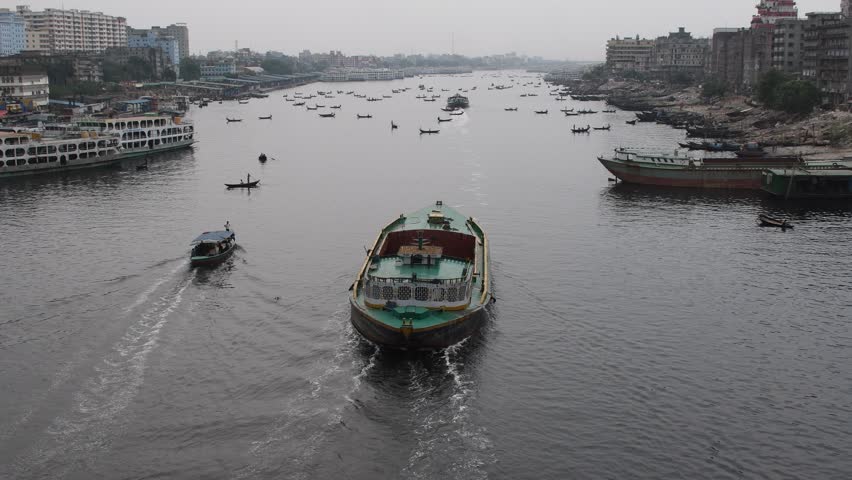 DHAKA, BANGLADESH – MAY 09: Small wooden boats are seen carrying passengers to cross the Buriganga river in Dhaka, Bangladesh on May 09, 2021.