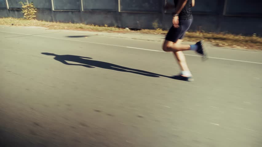 Professional Runner Exercising Along Urban Road During Morning Workout. Skilled Runner Exercising On Flat Urban Road To Improve Athletic Endurance. Healthy Lifestyle Activity. Runner Exercising Across Urban Road While Casting Long Shadow On Asphalt Surface. Athletic Movement Process. Fitness Training Exercise. Professional Labor Performance. City Environment Journey. Quality Control Speed. Seasonal Daily Workout. Outdoor Recreation Project. Physical Strength Development