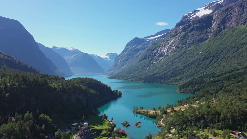 Spectacular view of Loen turquoise glacier water among epic mountain scenery with deep valley and snow capped mountains - Reverse aerial Loen Nordfjord Norway