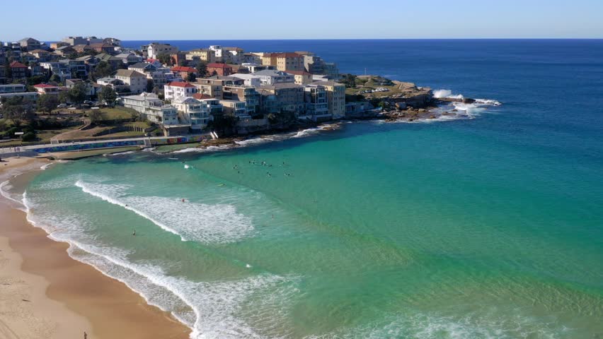 Waterfront Buildings In Ben Buckler Point With Tourist Swimming And Surfing In Bright Blue Sea. Summertime Scene In North Bondi, New South Wales. aerial drone