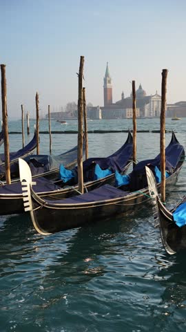 Gondolas on the Grand canal near San Marco square in Venice, Italy. San Giorgio Maggiore Cathedral in the background. Cityscape at sunset. Famous travel destination. Vertical video
