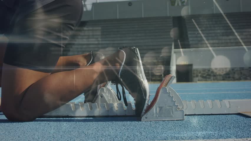 Sprinter shifting weight driving off blocks while numeric overlaying blue track for sports start. Athlete, outdoor, stadium, lane, running, speed, motion