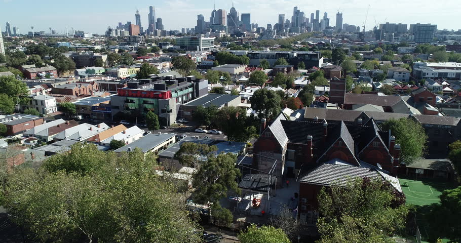 Smooth ascend and reveal of Melbourne CBD skyline and commission towers with old school in foreground.