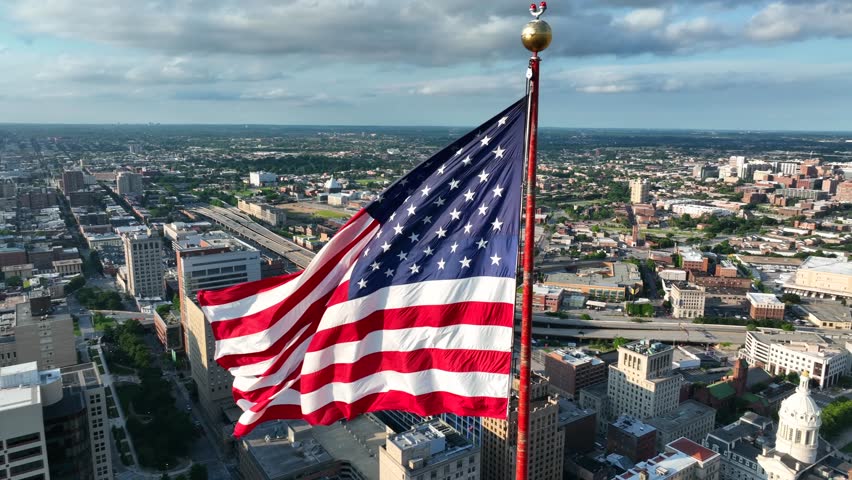 American flag waves in slow motion over Baltimore Maryland. City Hall visible.