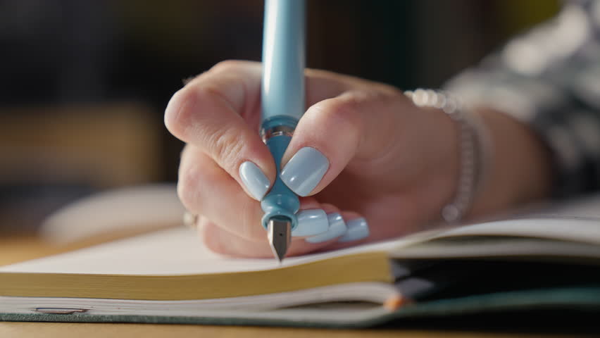Female Hand Writing in Notebook with Light Blue Fountain Pen, Planning Concept