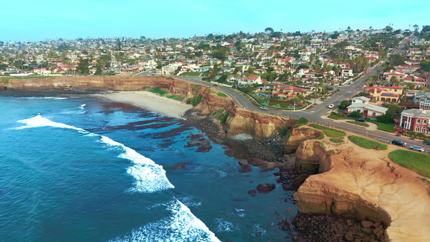 Drone shot of Del Mar city with coastal cliffs, sandy beach and Pacific Ocean waves along shoreline