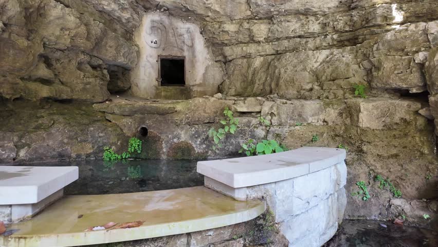 Weathered stone fountain features moss covered rocks