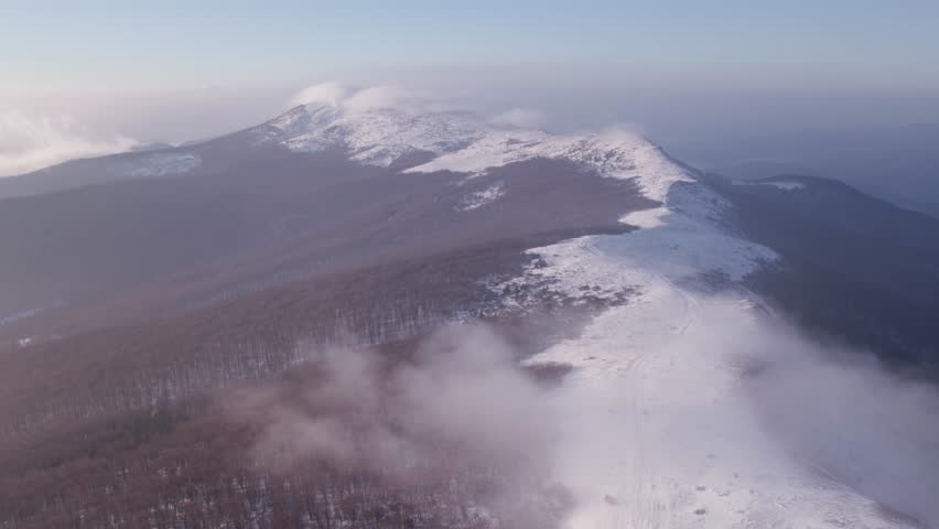 Drone flying high above large mountain ridge in winter