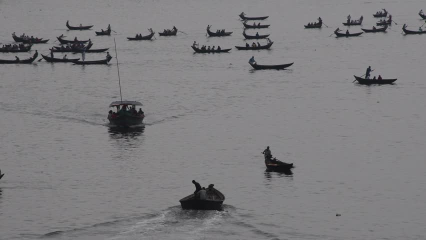 DHAKA, BANGLADESH – MAY 09: Small wooden boats are seen carrying passengers to cross the Buriganga river in Dhaka, Bangladesh on May 09, 2021.