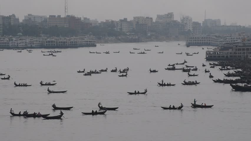 DHAKA, BANGLADESH – MAY 09: Small wooden boats are seen carrying passengers to cross the Buriganga river in Dhaka, Bangladesh on May 09, 2021.