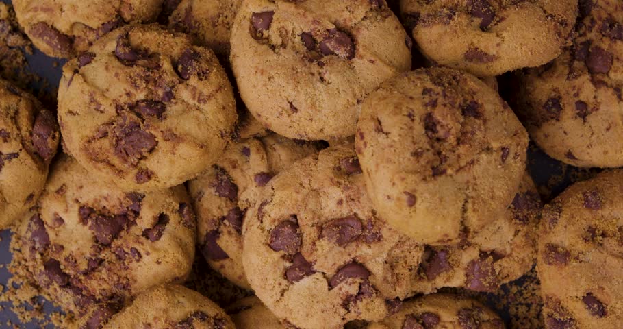birdseye close up shot of vegan cookies with vegan chocolate rotating from above on black background. static shot