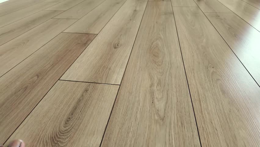 Close up camera moves along laminate flooring wood texture and pattern on newly installed floor